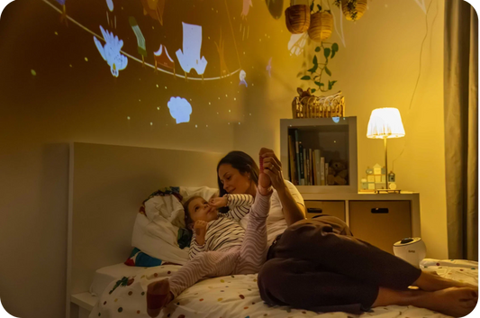 Mama und Kind liegen auf dem Bett und erzählen sich Geschichten zu den BiMA Lichterwelten.