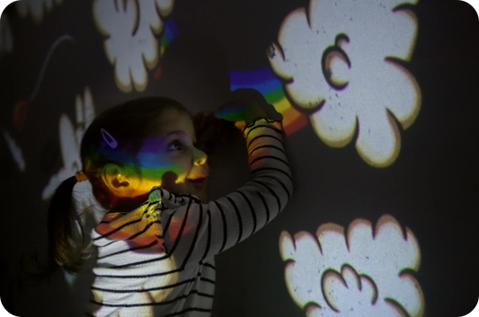 Kleines Mädchen spielt mit der BiMA Lichterwelt Wolkenzoo an der Wand.